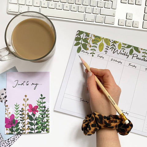 weekly planner with botanical design and cup of tea next to it