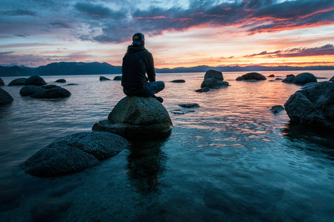 man sitting on stones looking out to sea